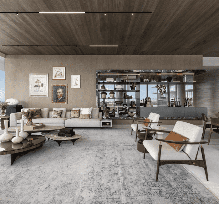 Modern high-rise living room in Coconut Grove featuring a wall of eclectic art, neutral-toned sectional sofa with colorful throw pillows, sculptural coffee tables, warm wood ceiling panels, and panoramic ocean views through floor-to-ceiling windows.