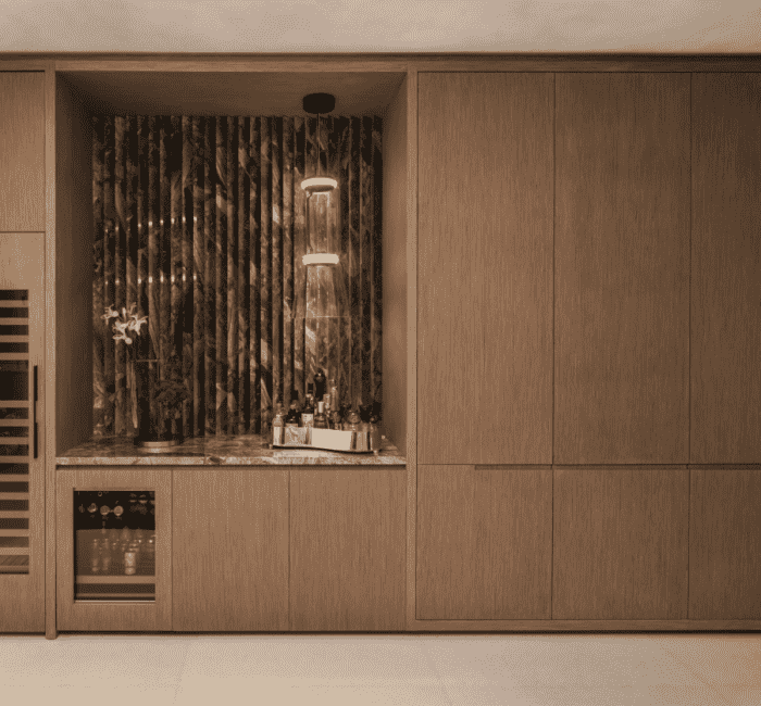 Built-in home bar with integrated wood cabinetry, fluted dark marble backsplash, under-counter beverage fridge, and pendant lighting in a modern Coconut Grove apartment.